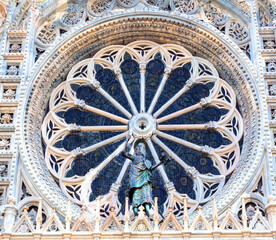 large, richly worked marble rose window with bronze statue of a saint, in an Italian Catholic church