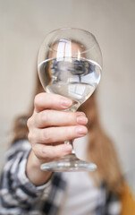 Close-up of woman holding a glass of water with outstretched hand capturing reflection and clarity