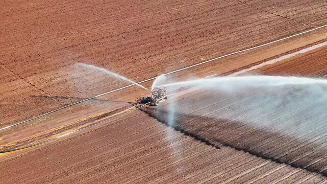 farm irrigator watering ploughed red dirt paddock field, farming agriculture agricultural equipment, water use conservation environment