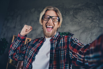 Selfie photo of young triumphant blond hair business man raised fist up crazy in office making video day at job workplace