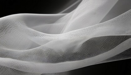 Elegant curves and shapes created by flowing delicate white tulle fabric on a black background