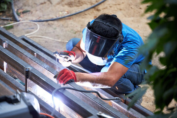 a worker welds a metal ladder in the garden