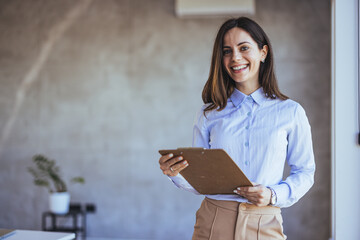 Confident Businesswoman Smiling Holding Clipboard in Modern Office