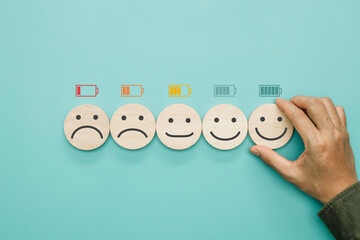 Work motivation, Battery, Energy, Employee happiness and positive attitude. Hand hold wooden with smile face emoticon with full level energy battery in the office