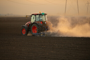 Fototapeta premium A red tractor prepares the land with a plow.