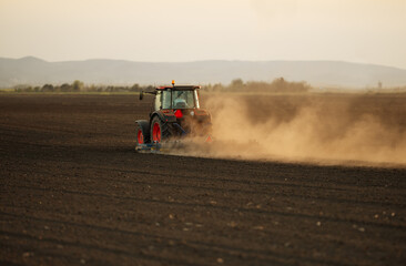 Naklejka premium A red tractor prepares the land with a plow.