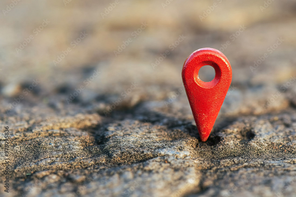Poster a close-up of a red location pin on a rough textured surface, symbolizing navigation and geographic 