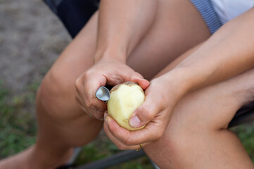 Women's hands peel potatoes with a knife, close-up