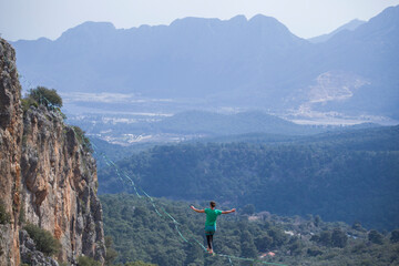 Obraz premium A tightrope walker walks along a cable stretched over a canyon.