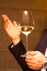 A glass of white wine held by a sommelier's hand 