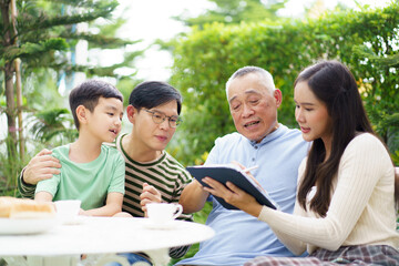 Multi generation Asian family relaxing in backyard garden together.