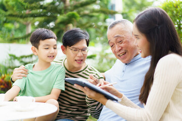 Multi generation Asian family relaxing in backyard garden together.