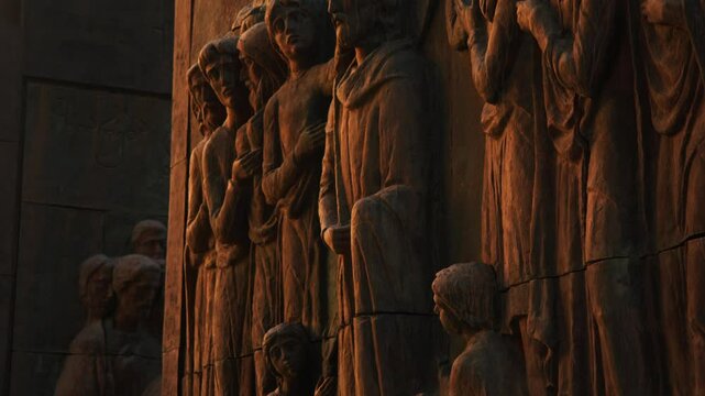 Bas-relief sculpture featuring the image of Jesus Christ, surrounded by apostles, is installed on the facade of the Chronicles of Georgia monument. The sculpture is illuminated by the setting sun's