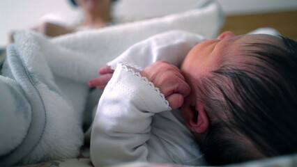 Newborn baby resting on a bed, peacefully lying on their side with a hand near their face. a tender moment of sleep, comfort, and early life in a warm, secure environment