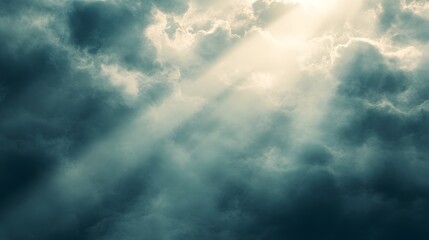 Obraz premium Dramatic Sunbeams Shining Through Moody Clouds in Majestic Heavenly Landscape