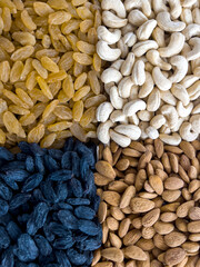 A grocery background of black and white raisins, cashews and almonds.