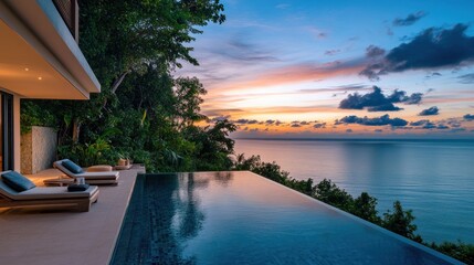 A serene sunset view over an infinity pool beside the ocean, surrounded by lush greenery.