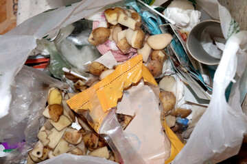 Plastic bag with food and household unsorted waste - horizontal photo, close-up. Potato peels,...