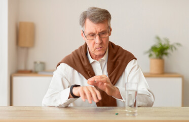 Elderly Gentleman Checking Time With Smartwatch Sitting At Table With A Pill And Glass Of Water At Home