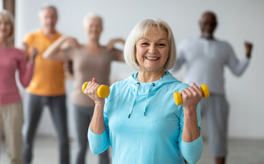 Multiracial group of senior people in sportswear doing strength building fitness exercises with...