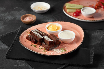 Rustic Garlic Borodinsky Croutons on Textured Pink Plate with Dipping Sauces – Dark Moody Studio Shot