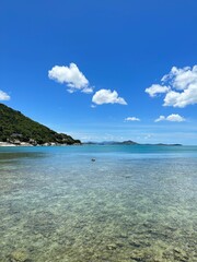 Sunny Day on a Thai Island with Turquoise Waters and Hills in the Background: A Perfect Tropical Escape with Feet in the Water