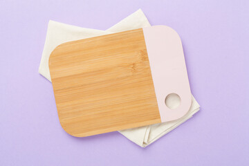 Cutting board with napkin on color background, top view
