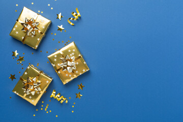 Golden gift boxes and confetti on color background, top view