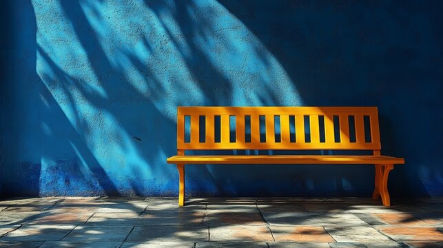 A vibrant orange bench casts intriguing shadows against a blue wall, creating a striking contrast in color and light.