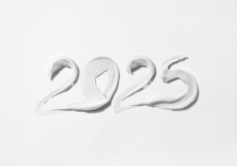 Writing 2025 with white cream, isolated on white background. Creating a swirl 2025 from white. Close up white cream detail photo isolated on white background