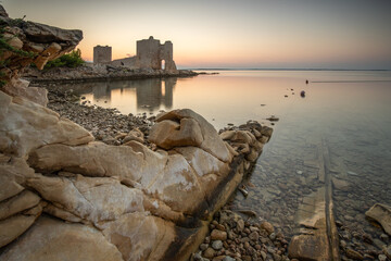 Castle ruins at dawn. Bay on the Mediterranean Sea with calm water at sunrise. Reflection of the sky and Mediterranean landscape of Kastelina Castle, Vir Island, Zadar, Dalmatia, Croatia, Adriatic Sea