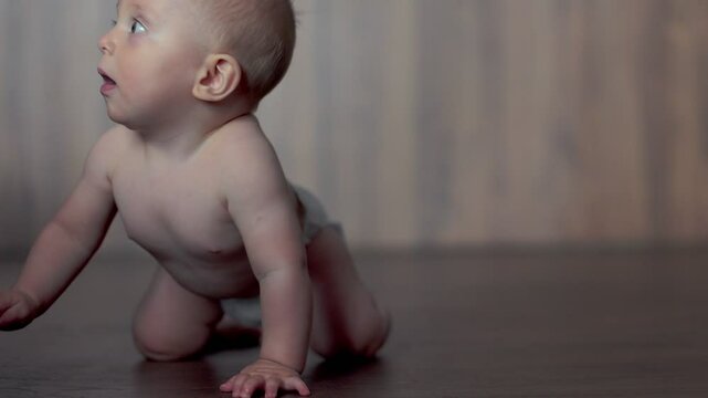 Cute little baby boy crawling over wooden parquet