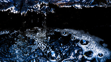 The gutter water splash, impressively black with foam that reflects sunlight, with copy space or negative space