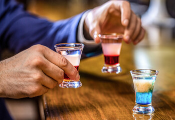 Male hands cheer with glasses of vodka and liqueur. Best friends toasting with cocktails. People...