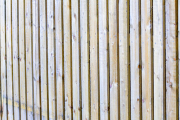 It is a close up view of wooden boards, unpainted bright wooden fence