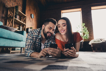 Full body photo of cheerful cute young couple lying floor device enjoy weekend have fun buy new...