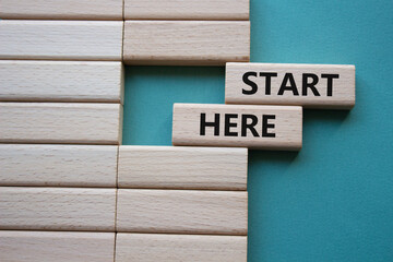 Start here symbol. Wooden blocks with words Start here Beautiful grey green background. Business...