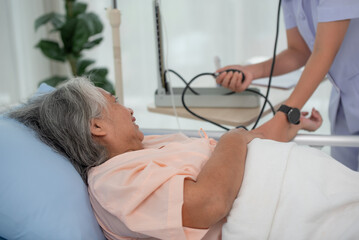 Asian nurse with tonometer measuring woman patient's blood pressure at hospital