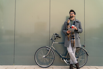 Young Caucasian Businessman with Bicycle Using Tablet While Enjoying Coffee