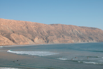 Surfer genie&szlig;en die Wellen vor einer beeindruckenden K&uuml;stenlandschaft