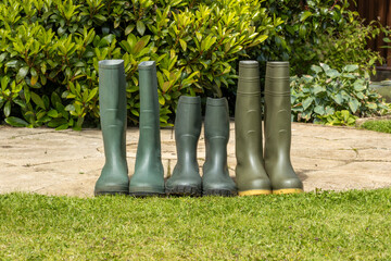 3 pairs mid and full height green rubber outdoor gardening wellington boots lined up in row on...