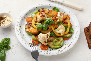 Plate with grilled vegetables and basil on white background