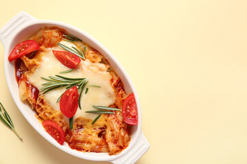 Baking dish of pasta with tomato sauce and cheese on beige background