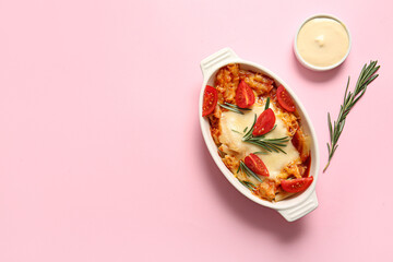 Baking dish of pasta with tomato sauce and cheese on pink background