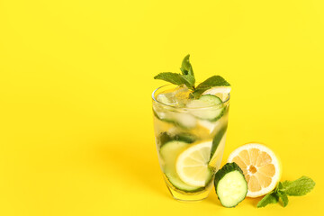 Glass of lemonade with cucumber and mint on yellow background