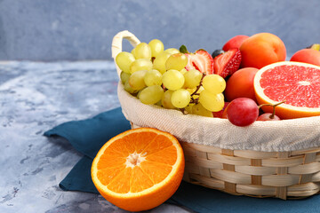 Wicker basket with different fresh fruits on blue background