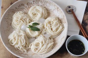 Somen is a traditional Japanese dish made with thin, white noodles typically served cold, often accompanied by a light dipping sauce called tsuyu. This refreshing summer dish is known for its delicate