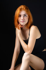 Cute red-haired girl, studio portrait on a black background.