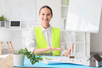 Female engineer with wind turbine model at table in office