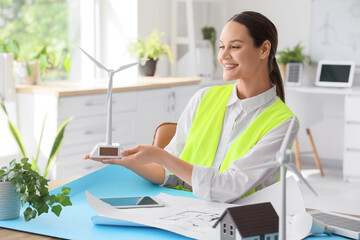 Female engineer with wind turbine model at table in office